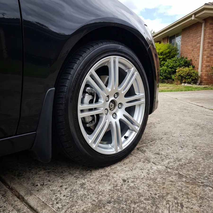 The same alloy wheel on a black sedan refinished bright and clean