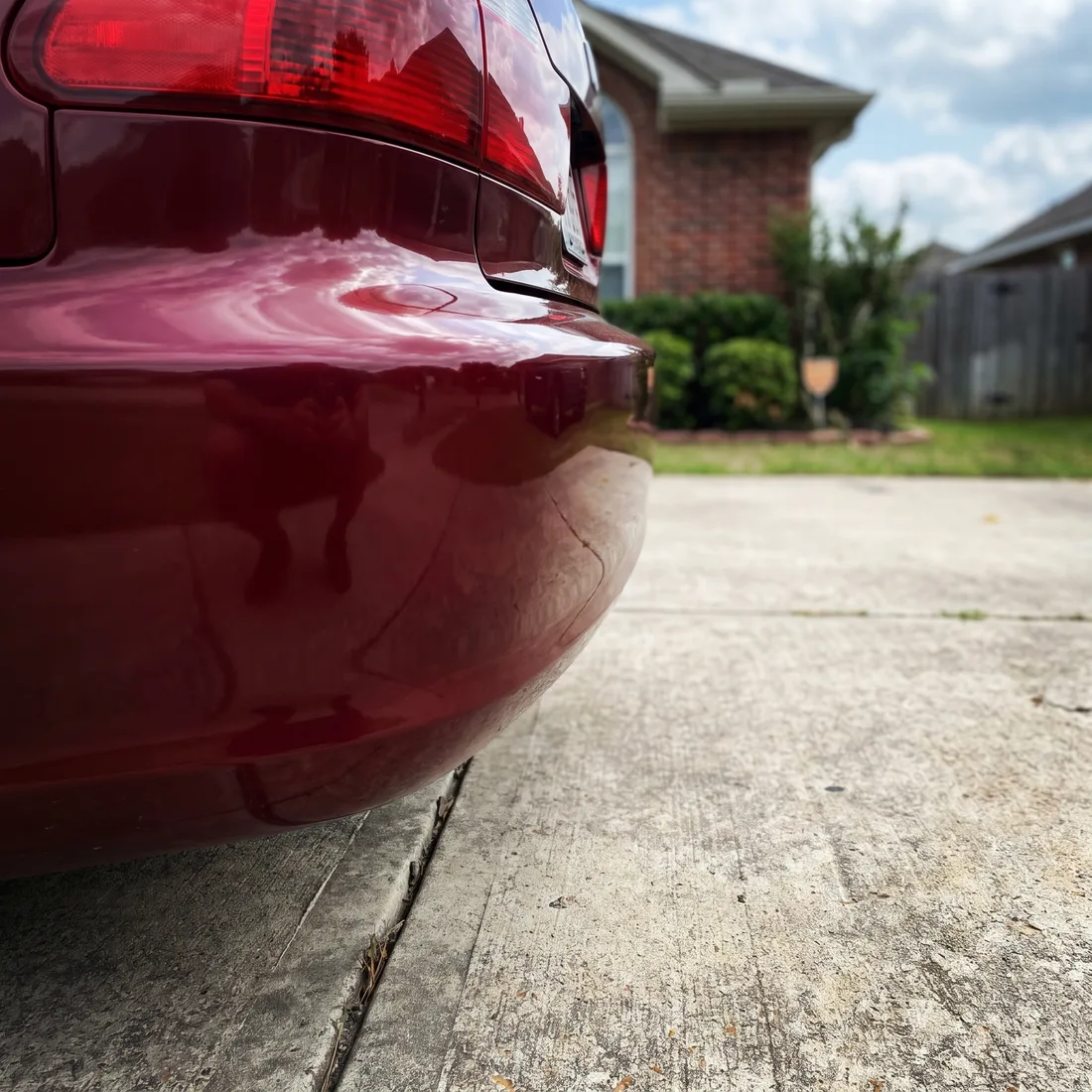 The rear bumper of a burgundy sedan after a mobile scuff repair