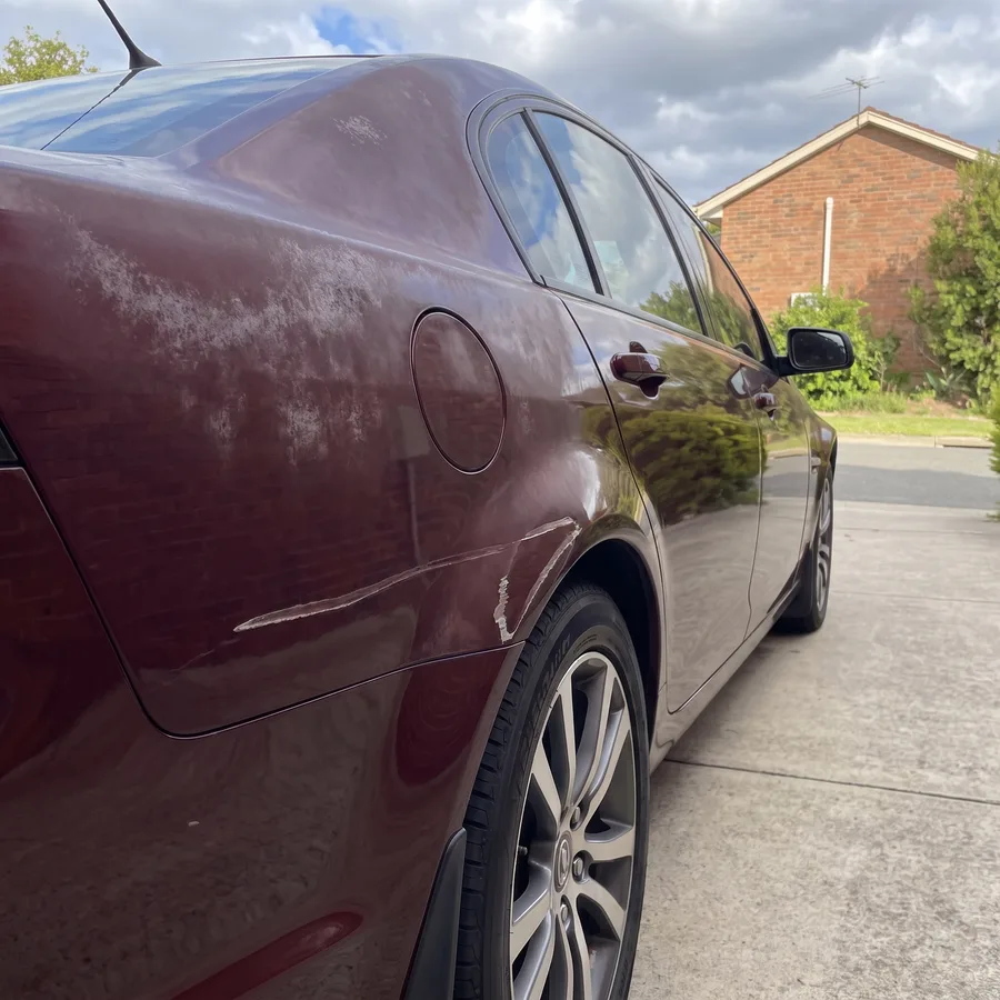 A sun-faded, grazed rear quarter panel before a colour-matched respray