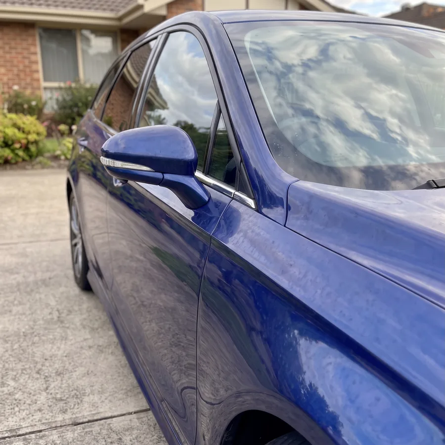 A blue wagon front guard oxidised, dull and water-spotted, before the repair