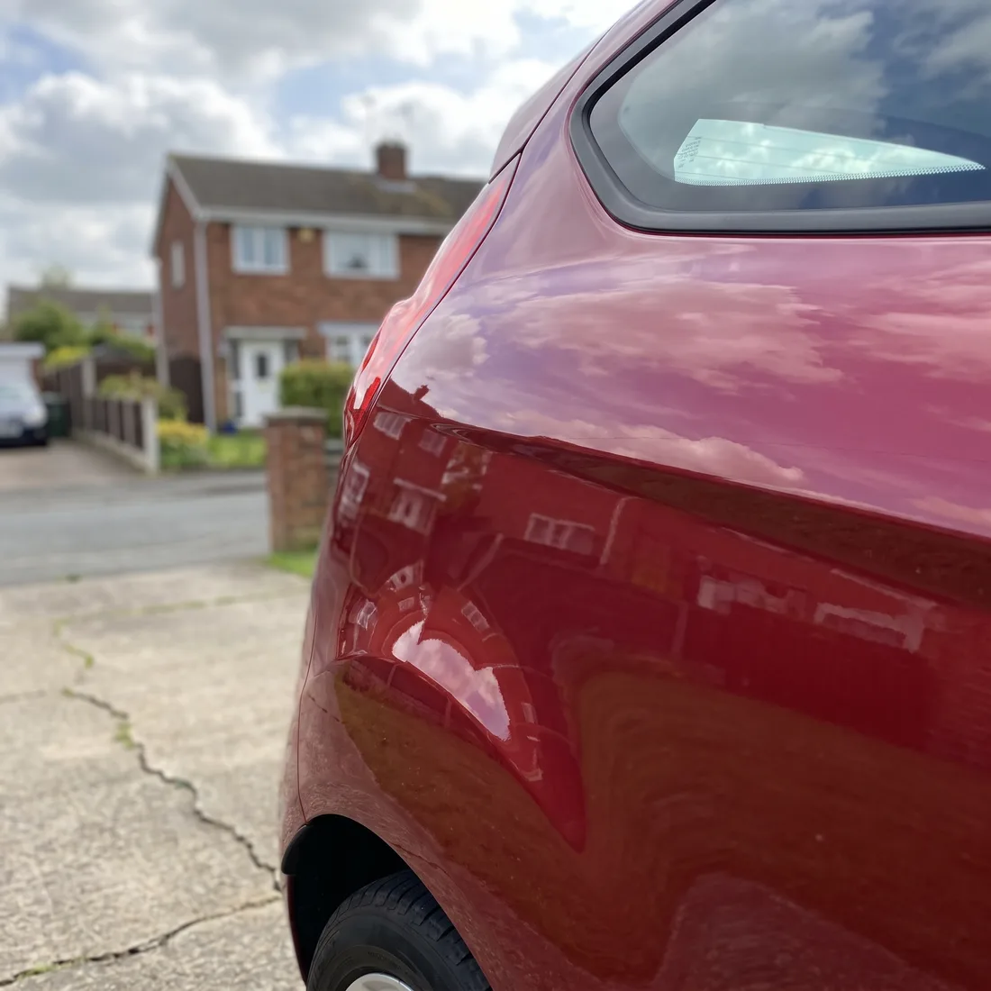 The rear quarter of a red hatchback after dent and paint work
