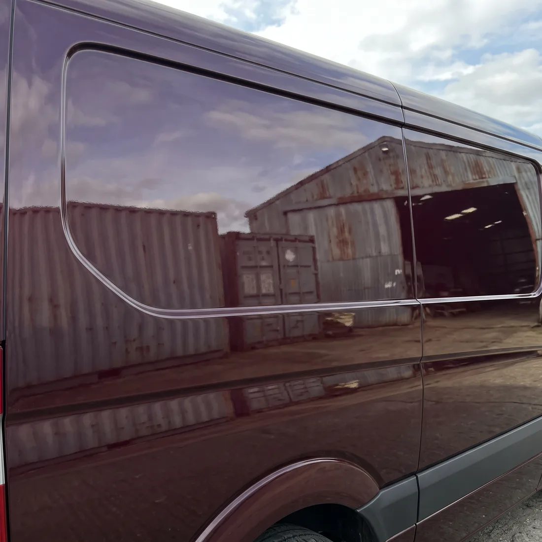 The side panel of a burgundy work van after a mobile paint repair