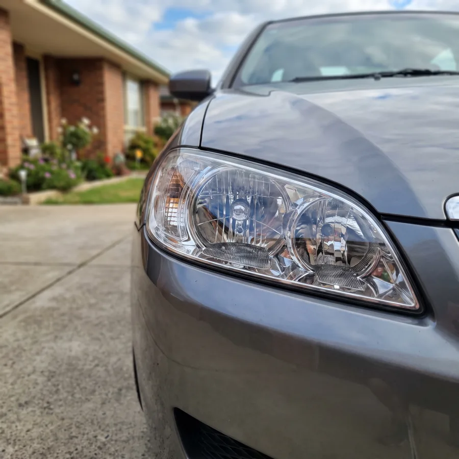 The same headlight lens on a grey sedan polished back to glass-clear