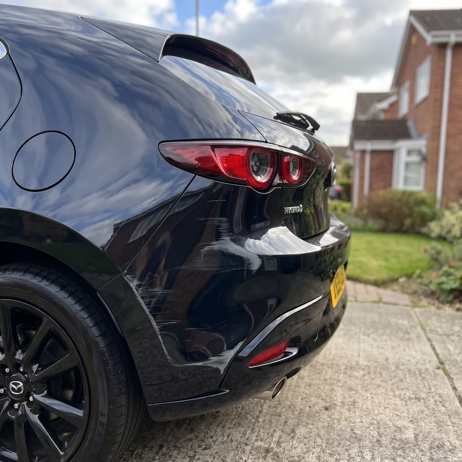 A black hatchback rear bumper corner kerb-scuffed and scratched, before the repair