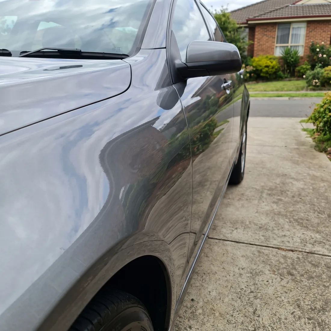 The front guard of a grey sedan after a mobile scratch repair