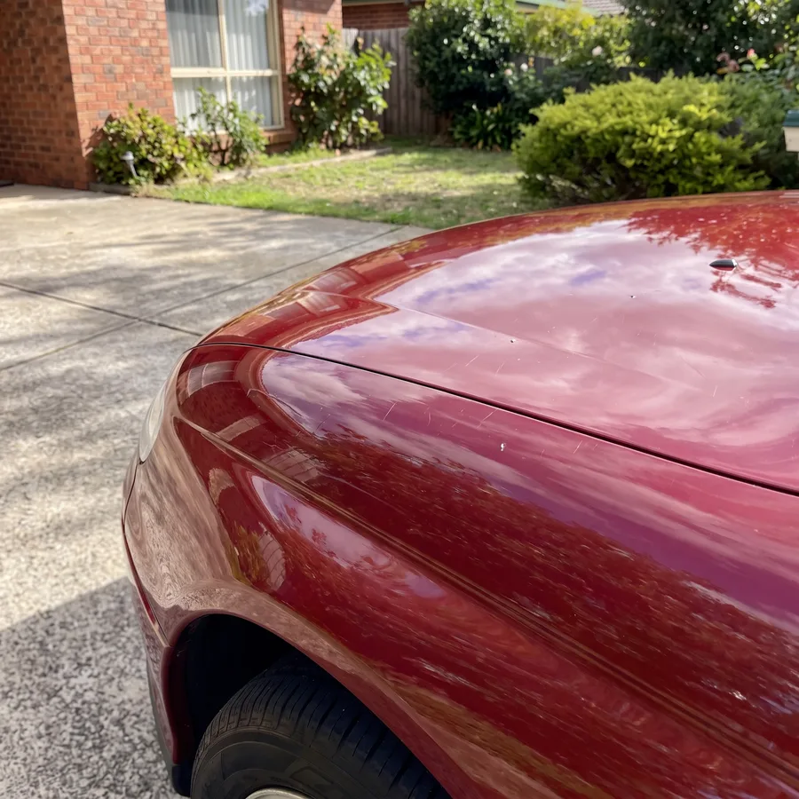 Stone chips and scratches on a red bonnet before a smart touch-up